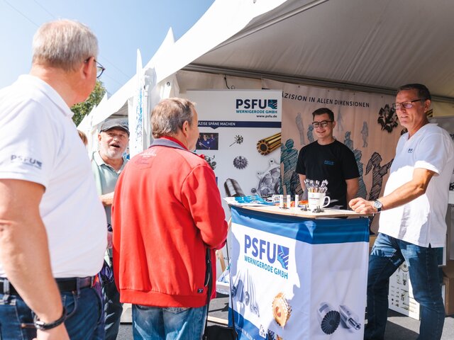 Zwei Mitarbeiter am Stand eines Wernigeröder Unternehmens im Gespräch mit Besuchern.