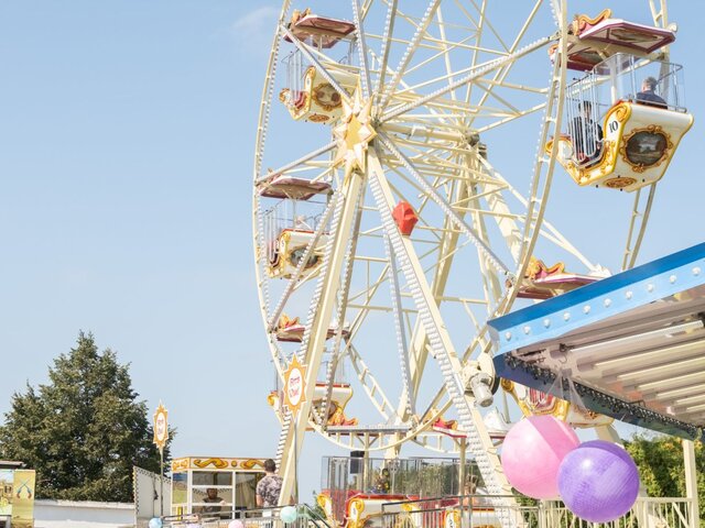 Nostalgisches Riesenrad mit goldverzierten Gondeln vor blauem Himmel.
